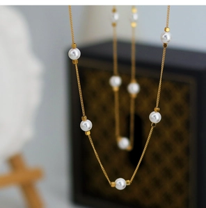 Detailed shot of gold-plated chain texture with polished white pearls and square beads