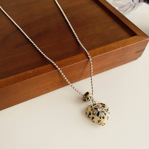 Detailed view of silver beaded necklace with diamond-encrusted flower on heart resin pendant
