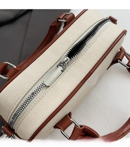 Detail view of the smooth silver metal zipper on the beige canvas Boston bag