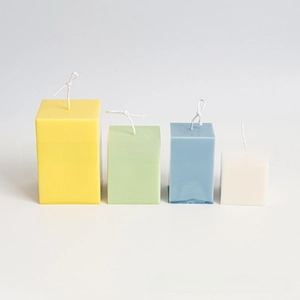 Four different sized colorful rectangular column candles in yellow, green, blue and cream