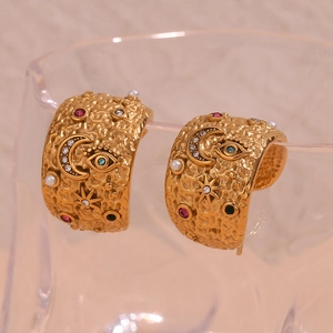 Detailed macro view of vintage hammered gold C-shaped earring with colorful zircon and pearls