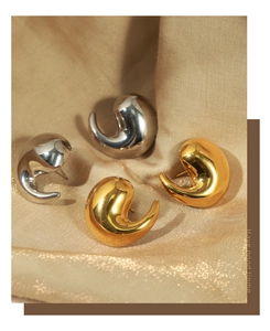 Close-up of artistic curved water drop earrings in polished gold and silver metal finishes