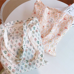 Detail of vintage floral cotton tote bag with a woven mat and magazine aesthetic setup