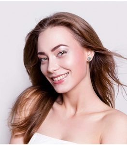 Close-up of a six-prong silver stud earring with a round-cut stone worn by a model