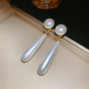 Detailed close-up of elegant pearl drop earrings with gold accents on a velvet jewelry box
