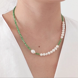 Detail of green beads and white freshwater pearl necklace on a model's neck