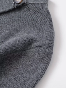 Close-up of dark grey knit fabric texture with a vintage tortoiseshell pattern button
