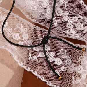 Detail showing the adjustable slide knot on a black cord necklace with gold tips