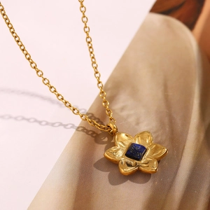 Macro shot of an 18K gold-plated flower necklace featuring a deep blue square stone pendant