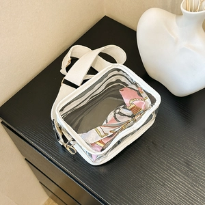 Detailed top view of a white transparent PVC crossbody bag with wide canvas strap
