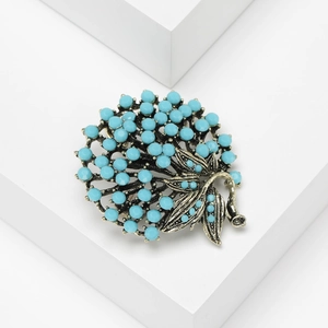 Vintage Turkish brooch with blue beads and rhinestone floral design on a white podium