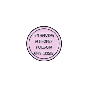 Macro detail of a round pink enamel badge with black lettering and zinc alloy edging