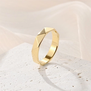 Primo piano di un anello d'oro geometrico con sfaccettature a rombo su pietra