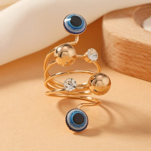 Spiral gold open ring with devil's eye beads and sparkling crystals on a wooden base