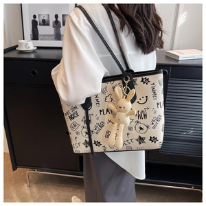 Detail view of white graffiti tote bag with black print and cute plush bunny charm