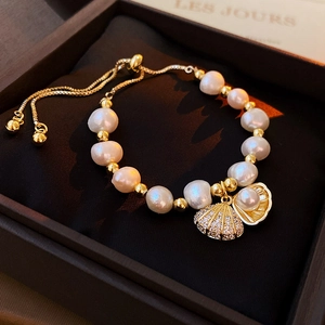 Macro detail of Baroque pearl bracelet with shell charms and adjustable gold slide clasp
