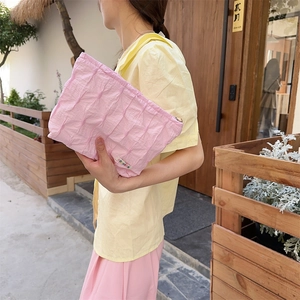 Close-up of pink quilted makeup bag showing pleated texture and brand logo label