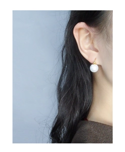 Close-up of elegant S925 silver pearl earrings worn on ear with golden metal hooks