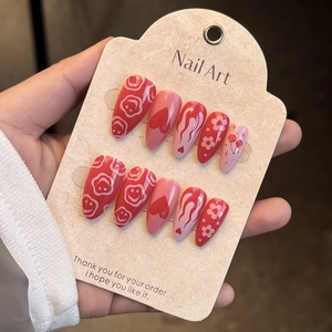 Detail of Y2K almond press-on nails with red cherry and heart patterns in glossy finish