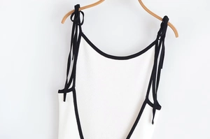 Détail de la mini robe en maille blanche avec liseré noir et bretelles à nœuds délicats