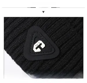 Detail of black knit beanie with a triangular Is't T patch and thick knit texture