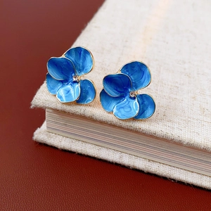Détail de boucles d'oreilles fleurs en émail bleu vintage avec centre en cristal