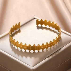 Detailed macro view of a gold-plated cuff bracelet featuring grid textures and beaded edges