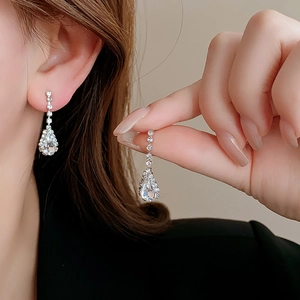 Close-up of geometric water drop tassel earrings with sparkling rhinestones in silver finish