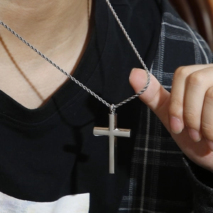 Nahaufnahme einer silbernen Kreuz-Halskette mit gedrehter Kette an einem männlichen Model