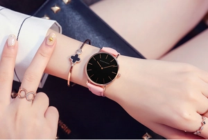Pink leather strap quartz watch with black dial and rose gold case on woman's wrist
