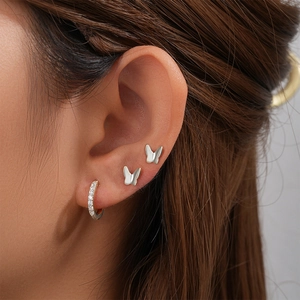 Close-up of silver butterfly studs and a gold diamond-encrusted hoop earring set