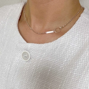 Detail shot of a silver olive bead necklace worn on a white tweed jacket outfit