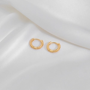 Elegant gold geometric hoop earrings with star relief texture on white silk background