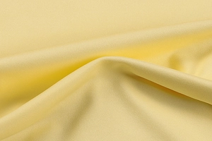 Detailed macro view of light yellow fabric texture with elegant pleats and smooth drape