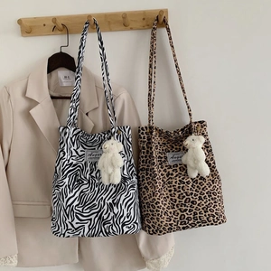 Detail view of leopard and zebra print corduroy tote bags with cute bear charm