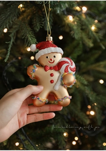 Detail of a golden gingerbread man ornament with red glitter hat on a Christmas tree