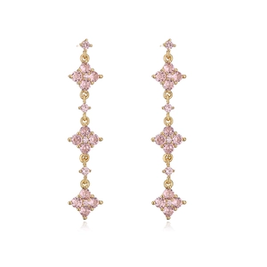Detail of 18K gold plated long tassel earrings with pink zircons on white background