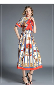 Detail of baroque print dress with red bow tie collar and short sleeves in silk texture