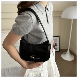 Side view of black crescent underarm bag with silver hardware worn in cozy indoor setting