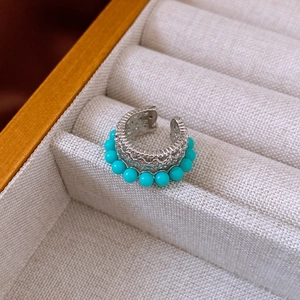 Detail of vintage silver ear cuff with sky blue beads and hollow metal design