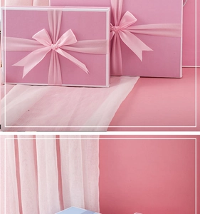 Detailed view of pink gift boxes featuring satin ribbon bows on a soft fabric backdrop