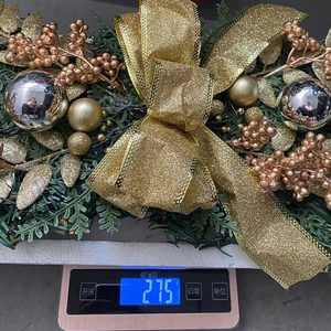 Detailed view of a Christmas garland featuring a gold glitter bow and festive ornaments