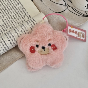 Detailed view of a pink plush star keychain with an embroidery face on an open book