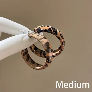 Handheld view of medium size leopard print acrylic hoop earrings in retro brown finish