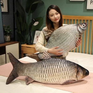 Realistic large fish plush pillow held by a woman in a cozy home bedroom setting