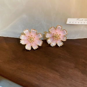 Macro detail of cherry blossom stud earrings with pink enamel and gold-plated edges