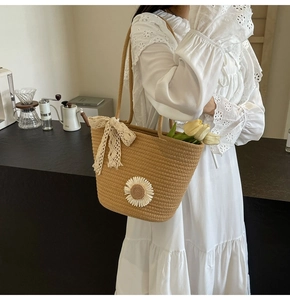 Detail of hand-woven tote bag with daisy embroidery and white lace bow in a lifestyle setting