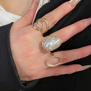 Three-piece gold ring set featuring baroque pearl, twisted design, and geometric patterns