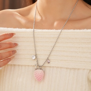 Close-up of pink strawberry pendant necklace with heart charms on white sweater