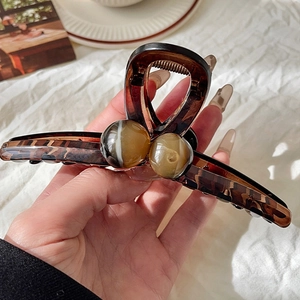 Detail of tortoiseshell amber hair claw clip with agate texture beads on white fabric